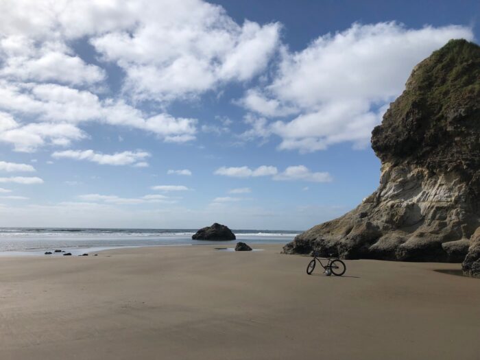 Cykel på slät strand vid höga klippor